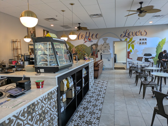 Inside the Grove café: marble counter, pastry case, and the Coffee Lovers mural with the St. Louis arch